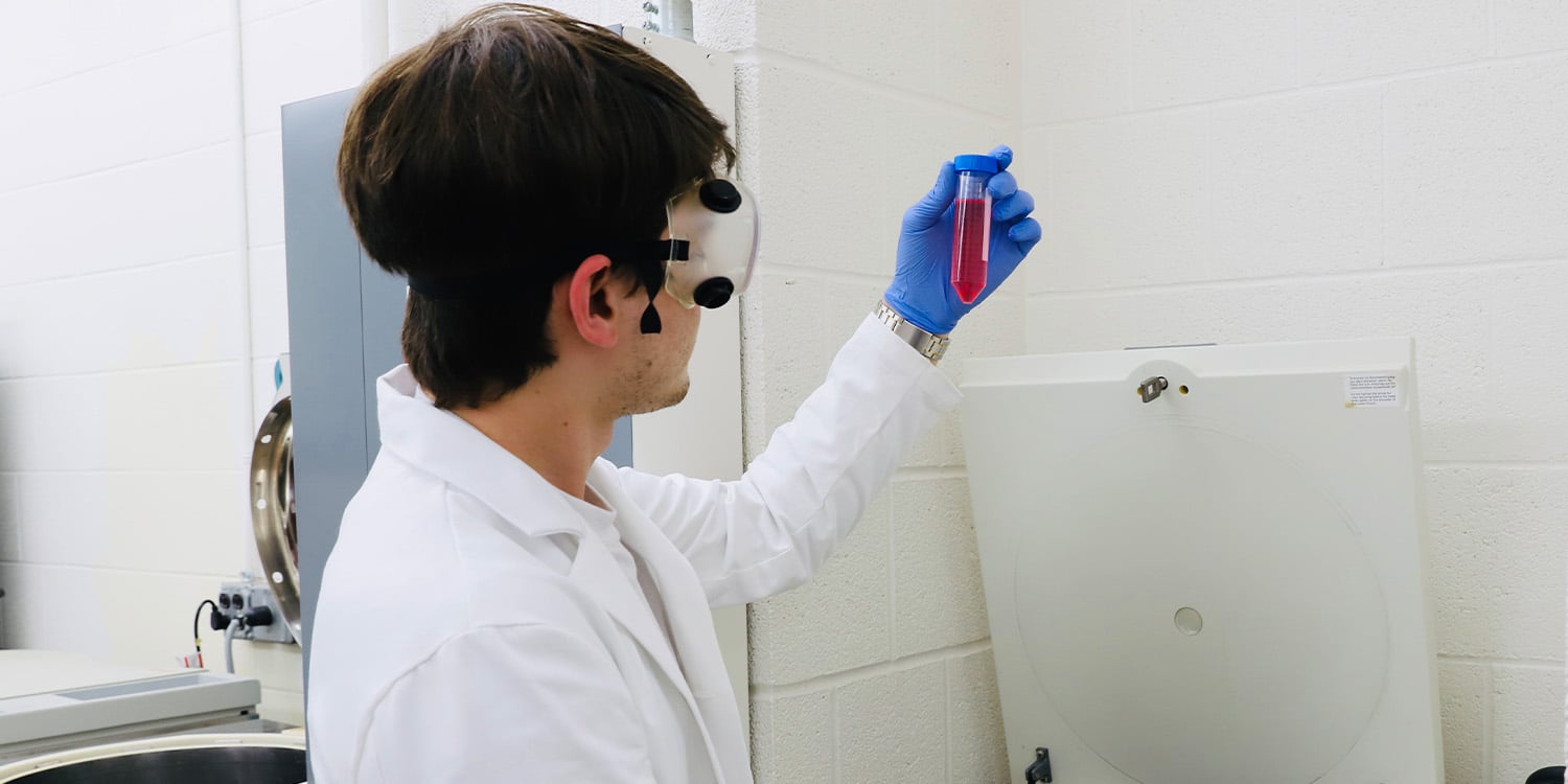 man holding a vial running tests in a lab